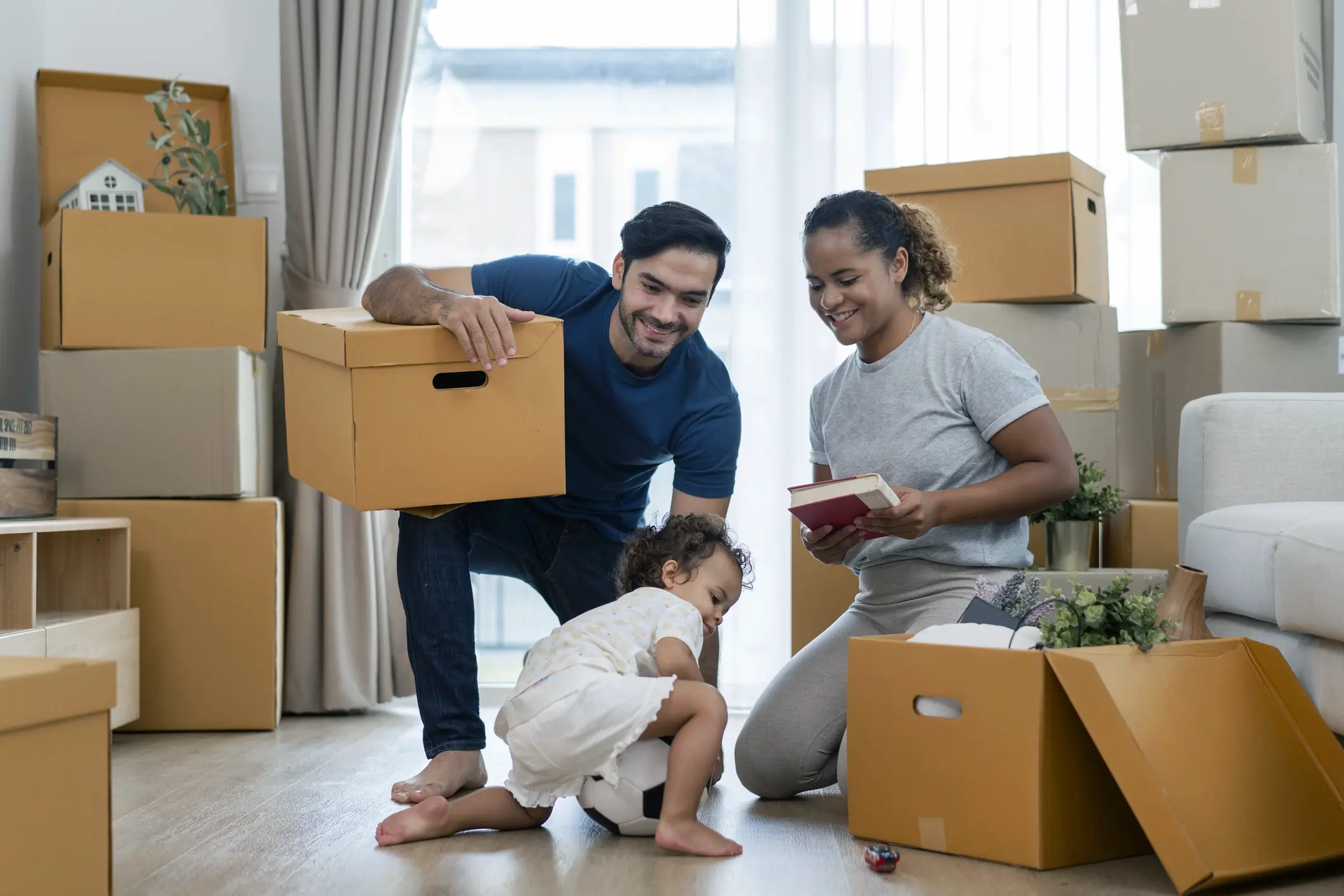 Family unpacking moving boxes in their new home, after relocating to a new state. Used to highlight state-specific homeowners insurance requirements.