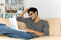 man sitting on a couch using a laptop