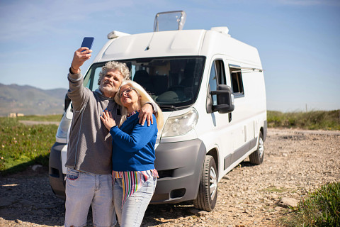 couples taking a selfie in front of their white RV used to show the peace of mind that comes with RV insurance