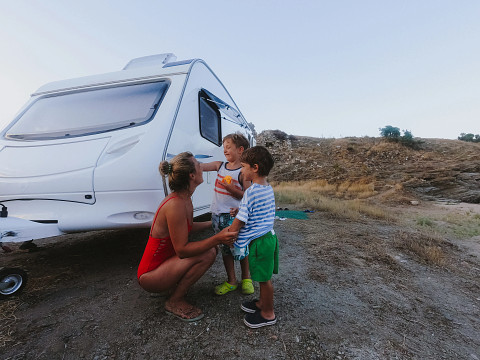 a mother talking to her two kids next to their white travel trailers